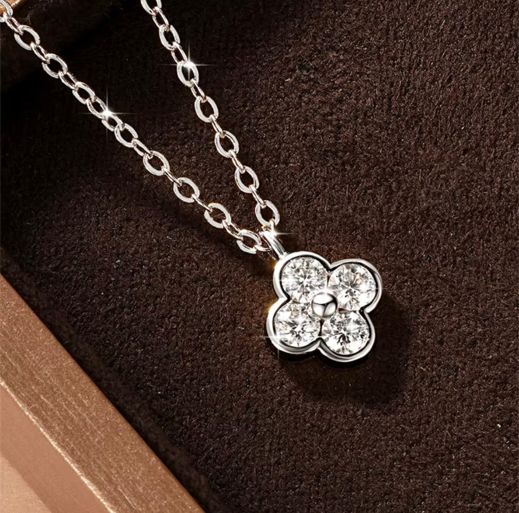 Klavertje vier moissanite ketting zilver en goud op donkere achtergrond