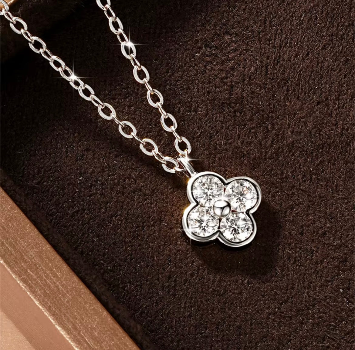 Klavertje vier moissanite ketting zilver en goud op donkere achtergrond